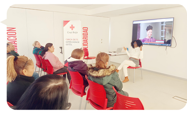 Niurys Núñez facilitando una capacitación en una sala de la Cruz Roja, interactuando con los asistentes mientras una presentación se proyecta en la pantalla.