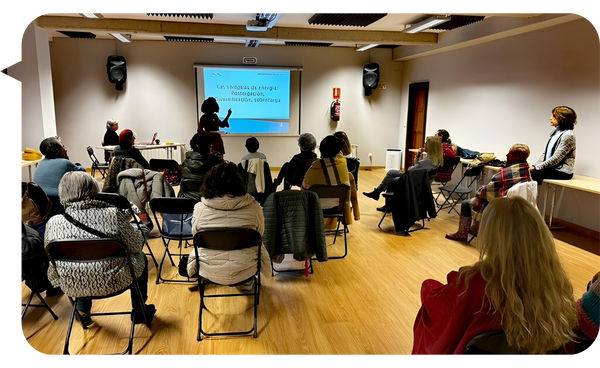 La conferencista Niurys Nuñez imparte una charla frente a un grupo de personas sentadas en una sala, con una presentación proyectada en pantalla.