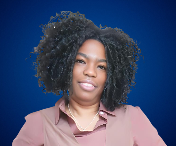 Retrato profesional de Niurys Núñez con blusa en tonos tierra y un fondo azul, proyectando confianza y liderazgo.